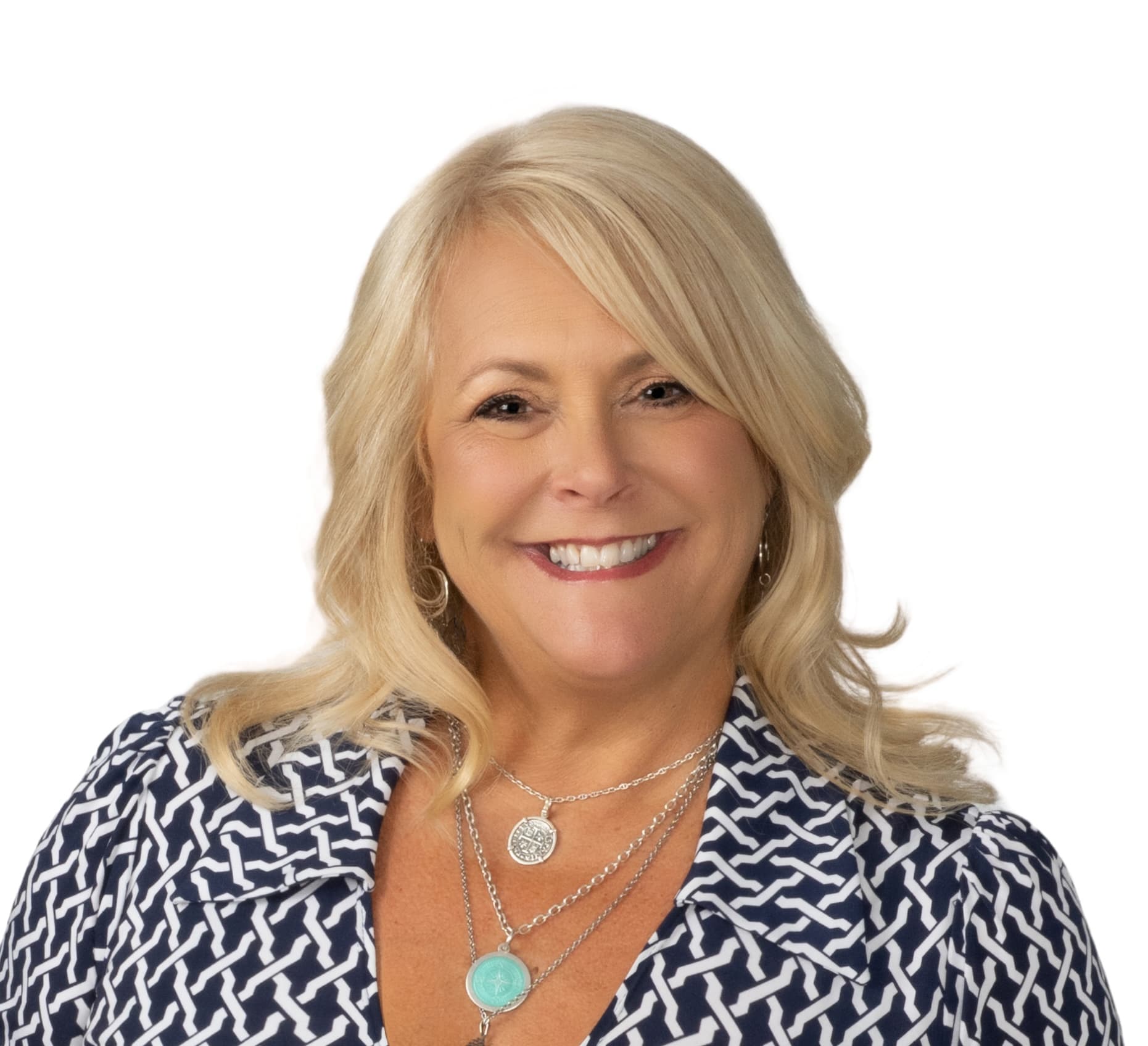 Portrait of Gina Ghiglietti, Managing Director of Stroll St. Pete, smiling in a navy and white patterned top with layered silver necklaces